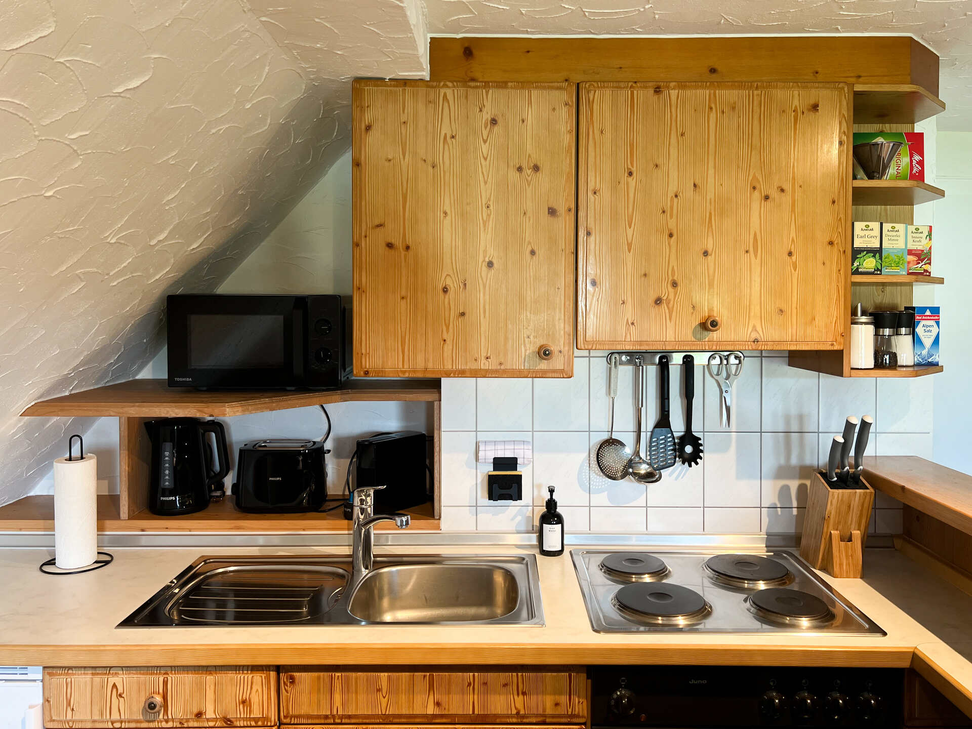 Kuechenzeile mit Kochfeld, Mikrowelle und Geraeten