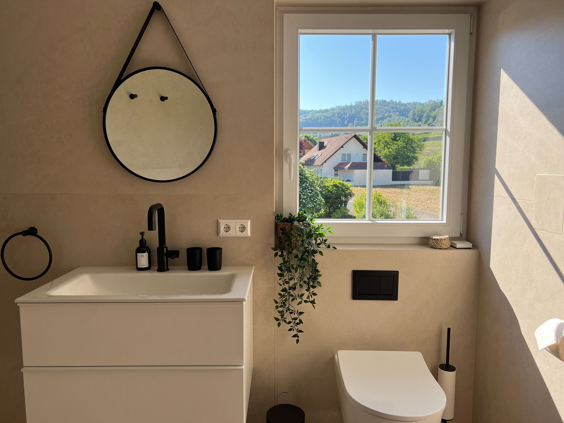 Waschbecken mit rundem Spiegel und schwarzer Armatur im Badezimmer