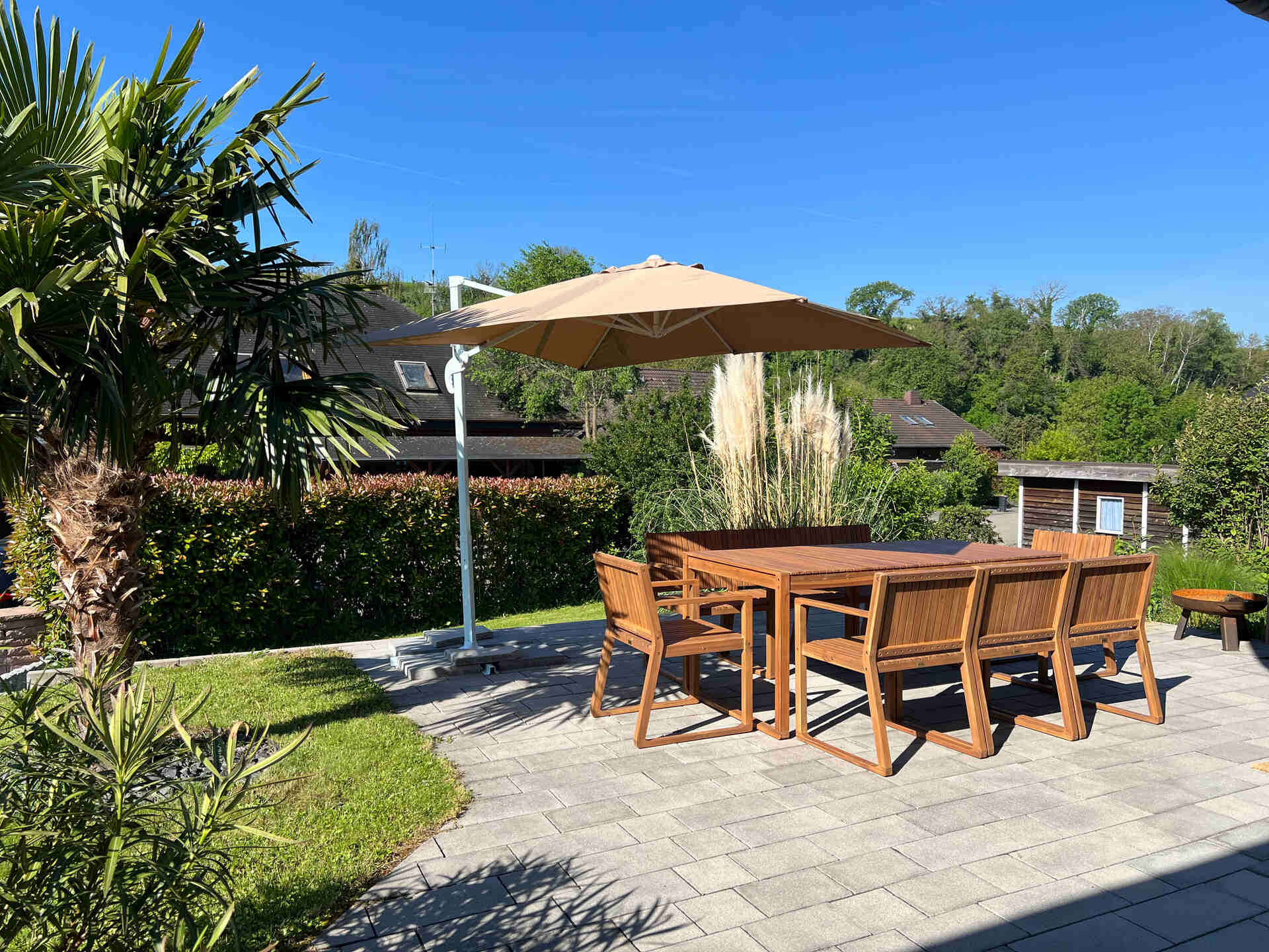 Terrasse mit Esstisch, Sonnenschirm und Gartenblick