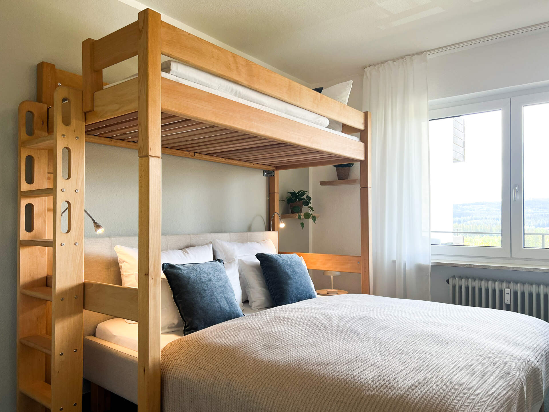 Doppelbett mit Hochbett und Fensterblick