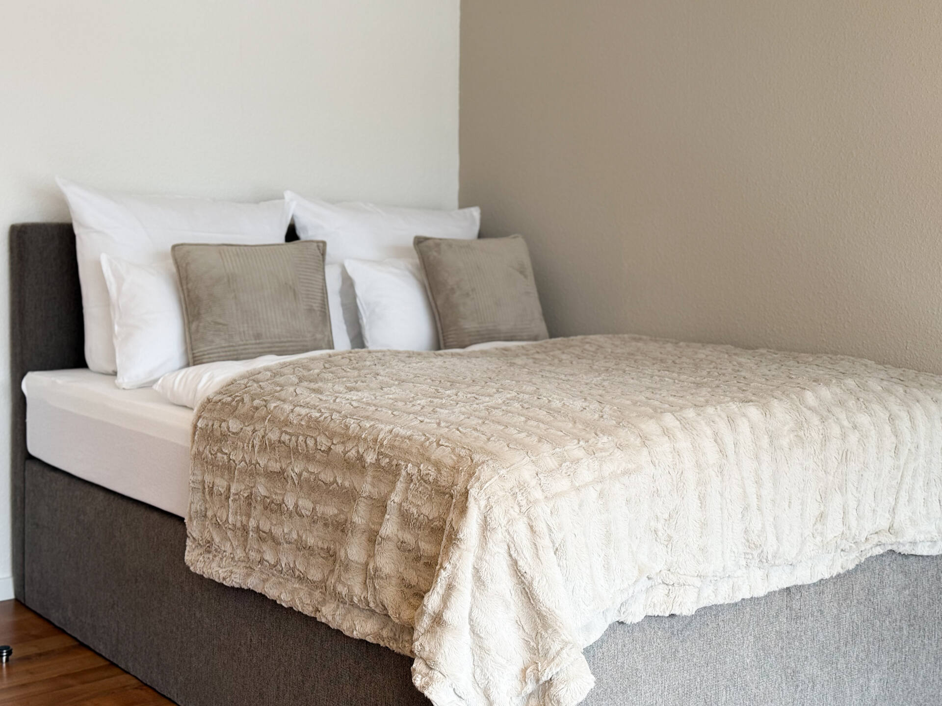 Doppelbett mit beiger Decke und Zierkissen