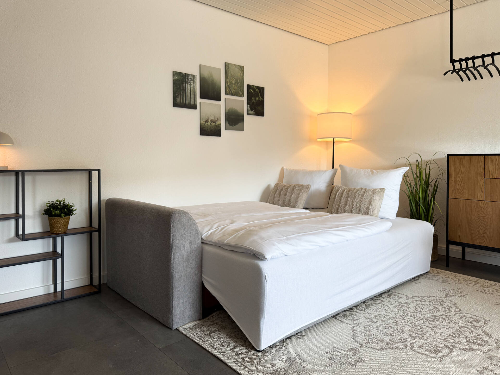 Helles Wohnzimmer mit Schlafsofa und Stehlampe