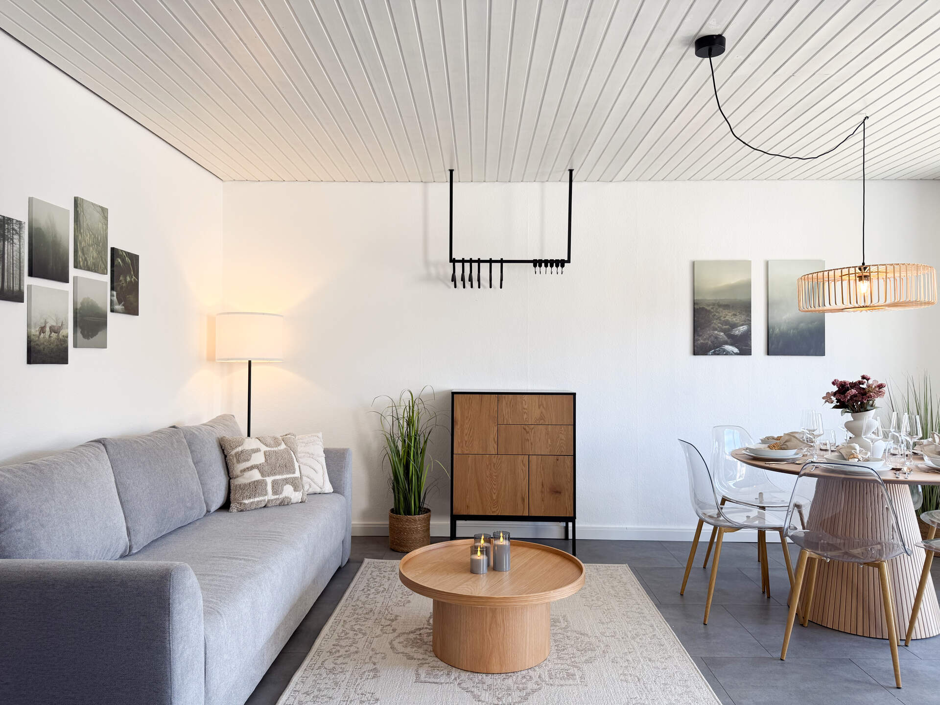 Sofa mit Wandbildern und Garderobe mit Kleiderbuegeln