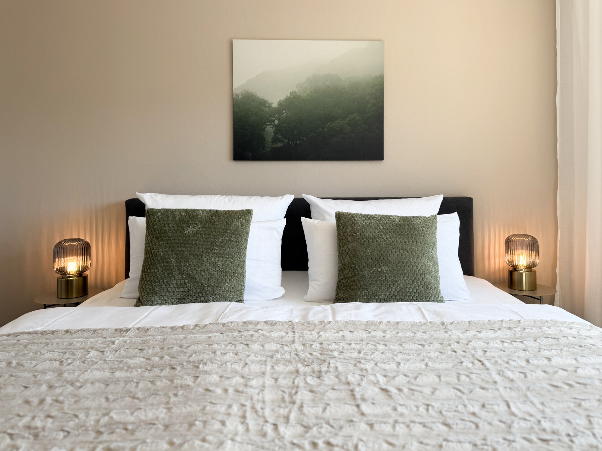 Doppelbett mit gruenen Kissen und Wandbild