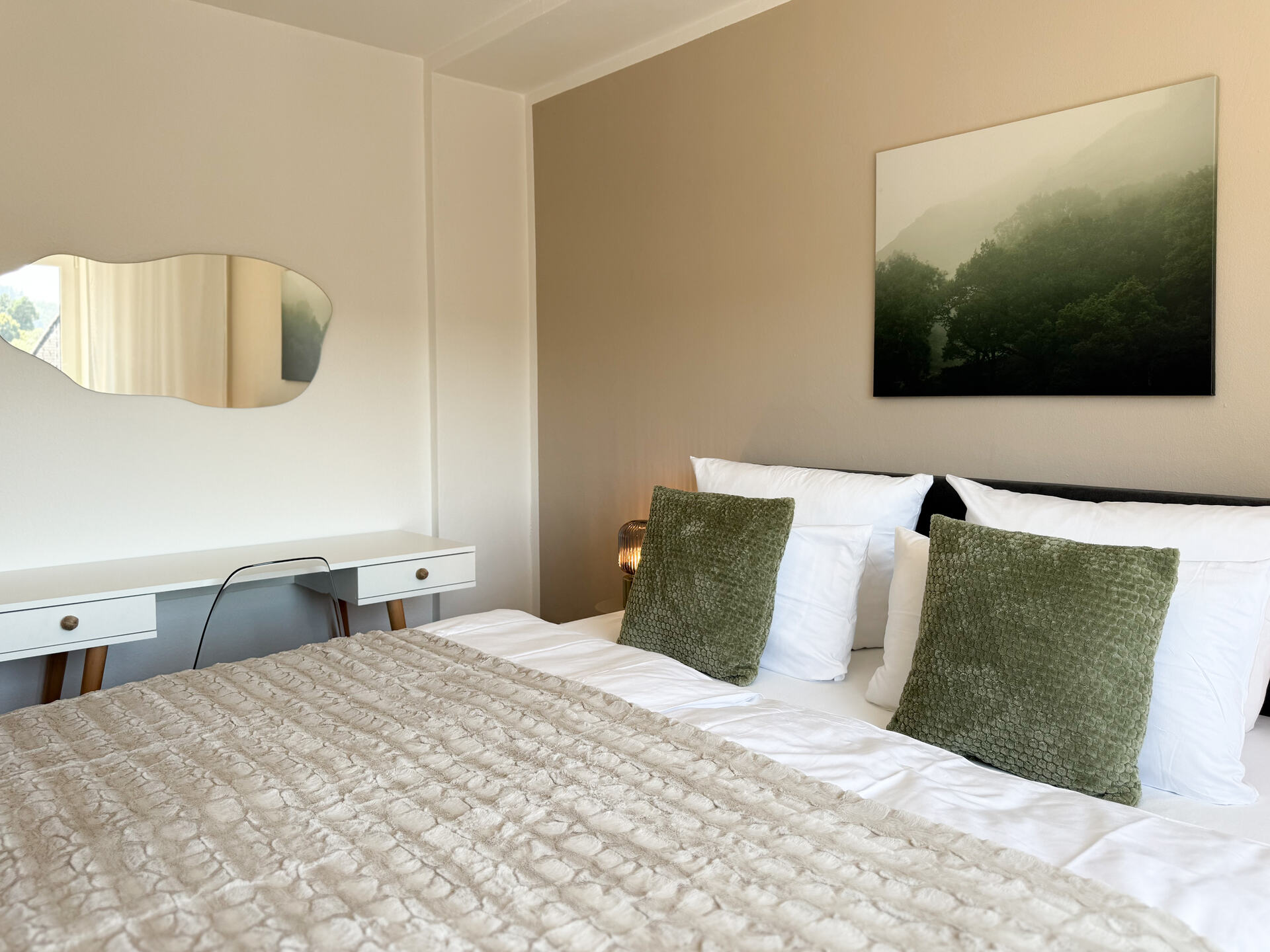 Bett mit gruenem Kissen und Schreibtisch