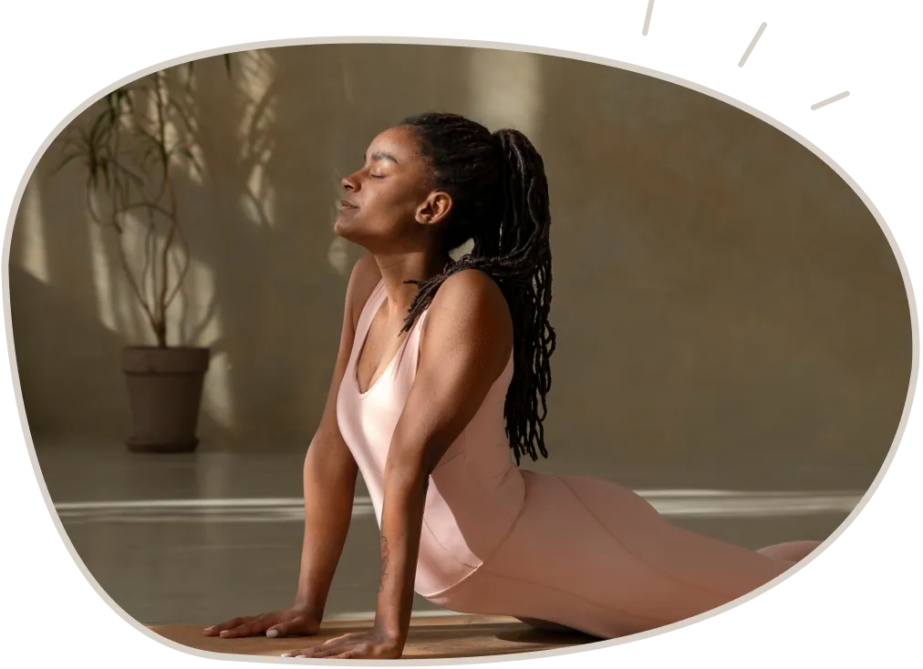 Woman in pink activewear practicing yoga indoors in upward dog pose with eyes closed.