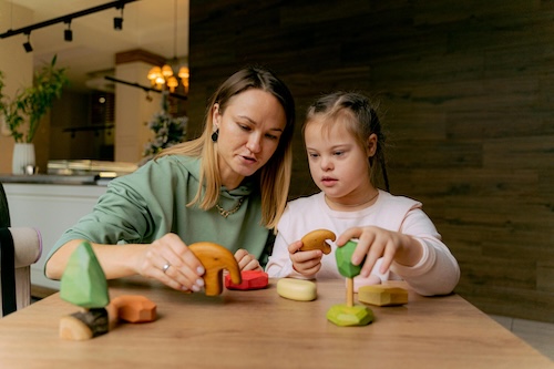 Image of a friendly female Support Worker helping a young child fingerpaint