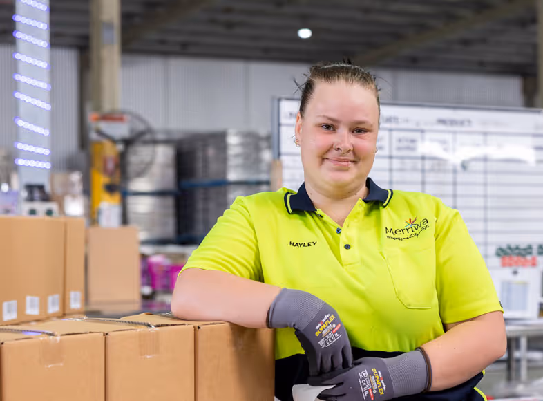 A lady wearing fluro tshirt standing next to some boxes.