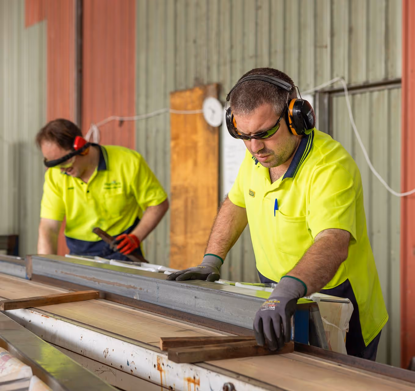 Two staff member wearing fluro shirts, working next to a conveyor.