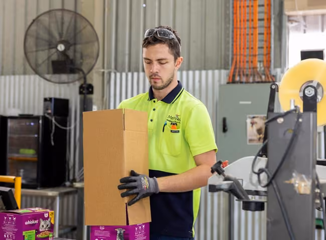 A man in fluro putting a box over another box