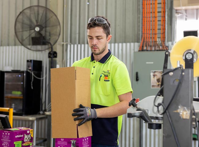 A man in fluro putting a box over another box