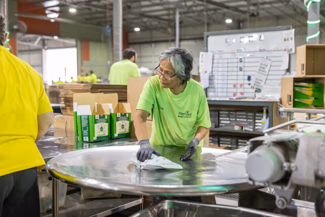 A person standing in front of a turn table picking up a bag of product.