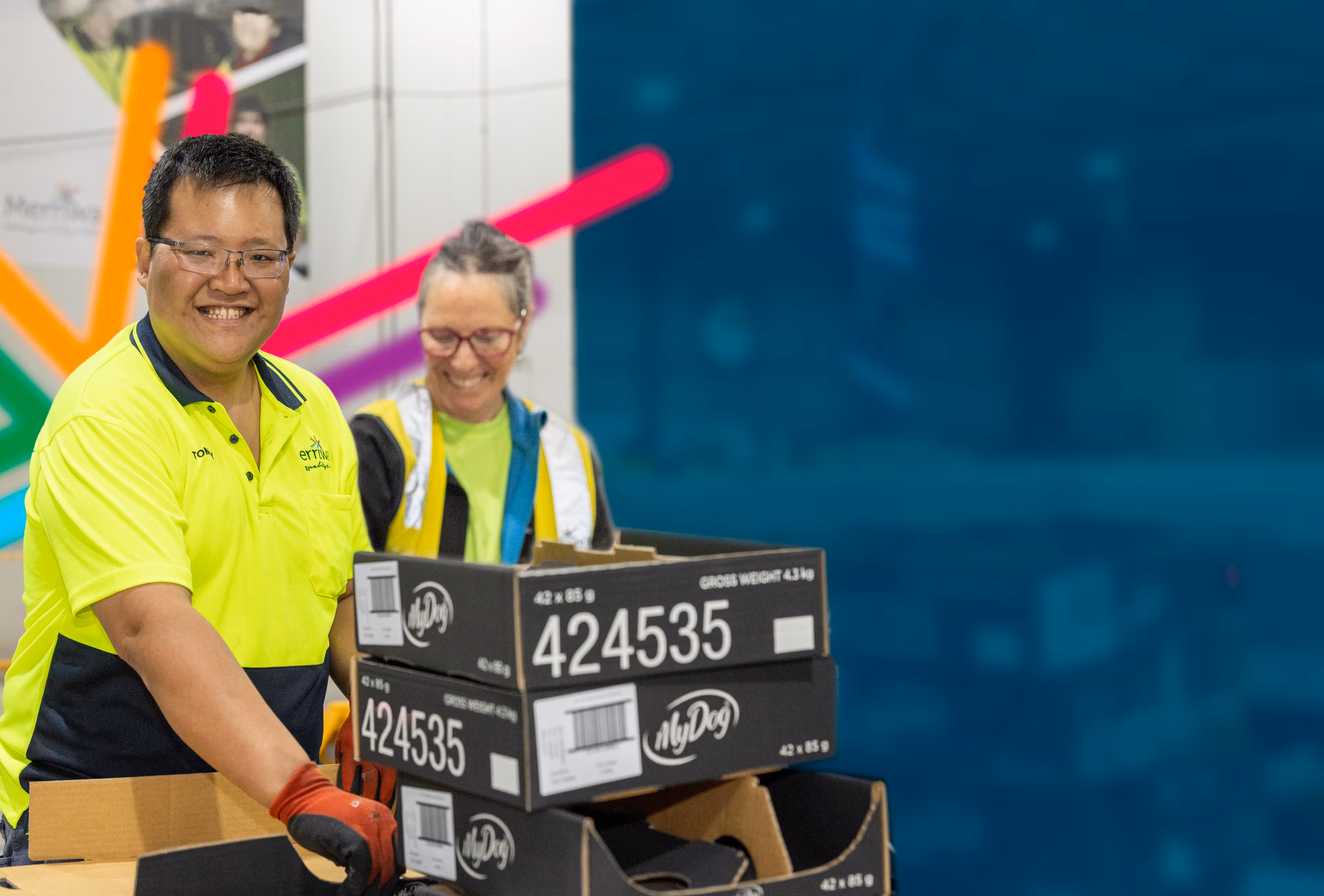 Two people working on a production line with boxes
