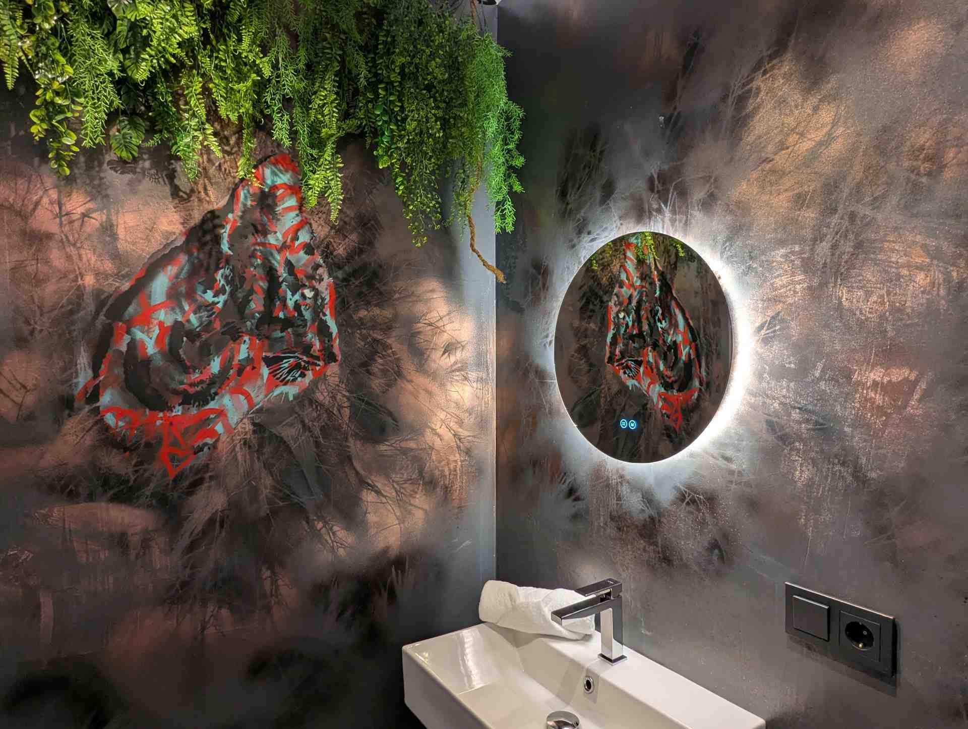 Waschbecken mit beleuchtetem Spiegel und moderner kunst