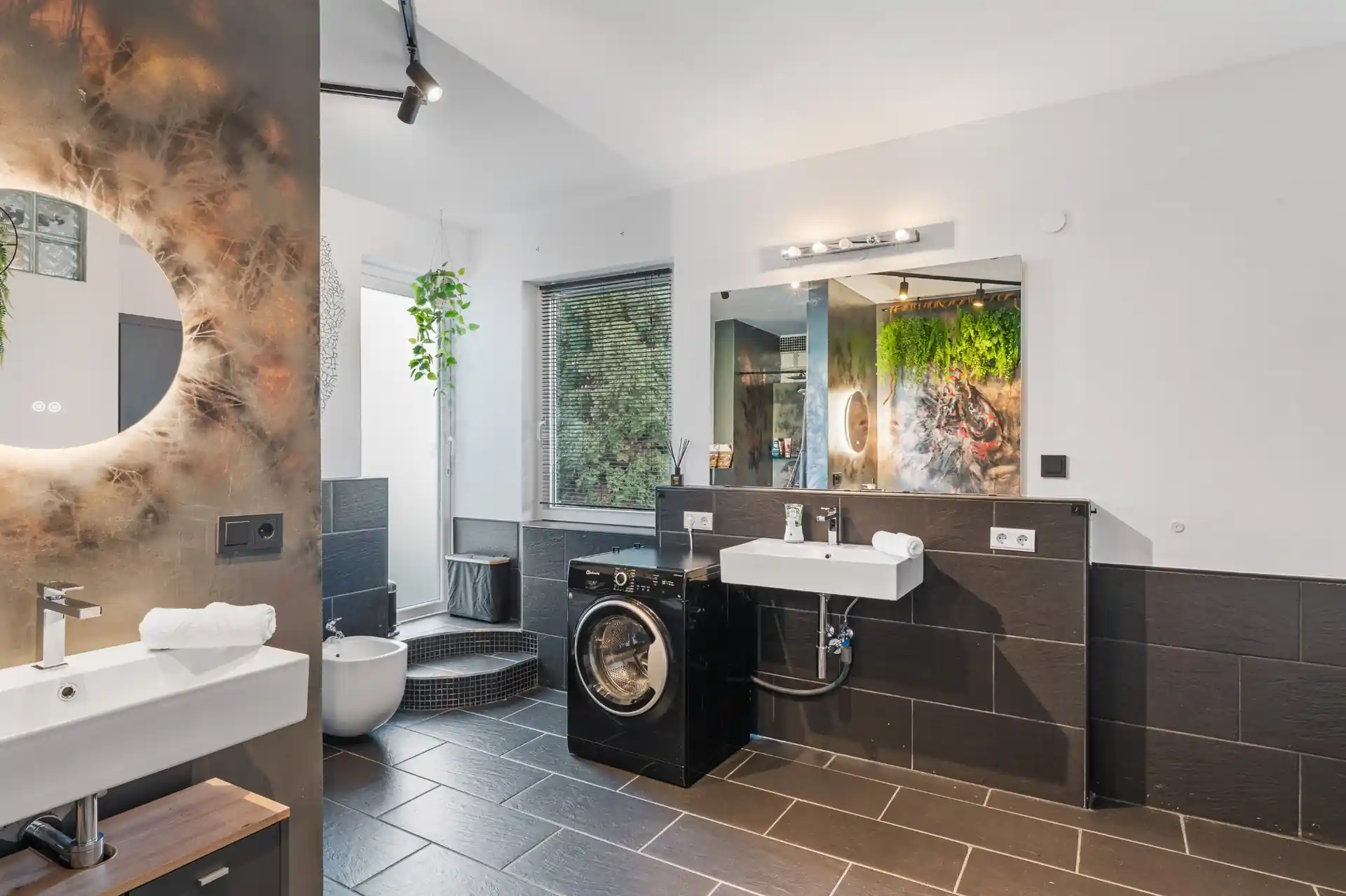 Badezimmer mit Waschbecken, Waschmaschine und Spiegel im Ferienhaus Die 16 Rosenfeld