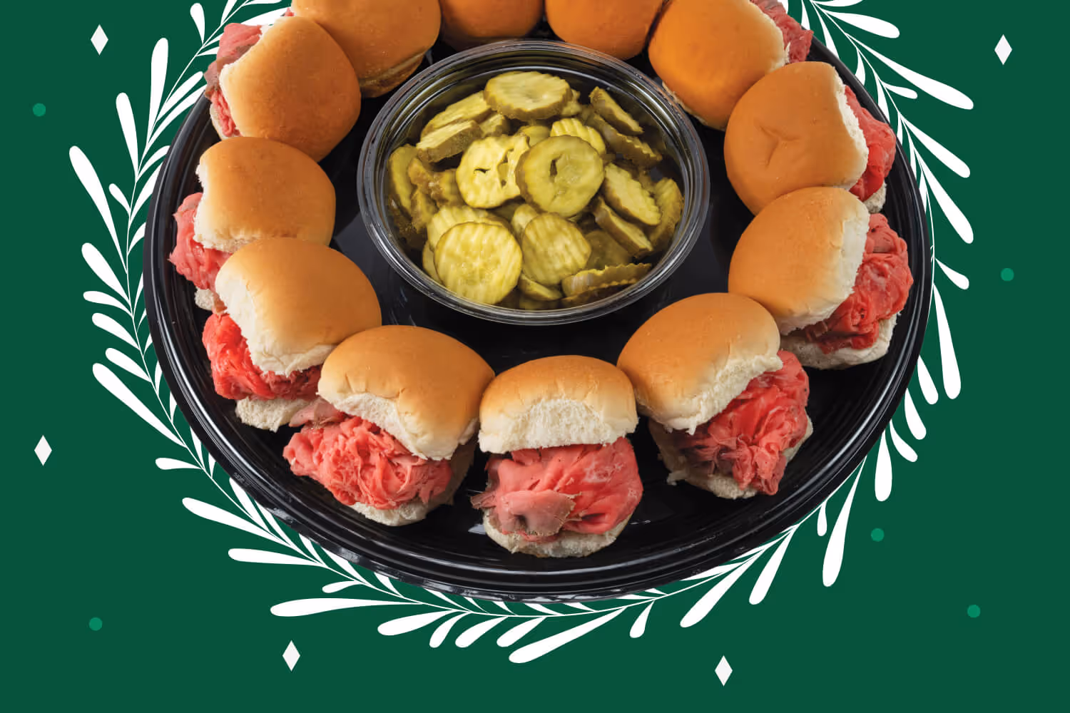 Tray of roast beef slider sandwiches arranged around a bowl of pickle slices.