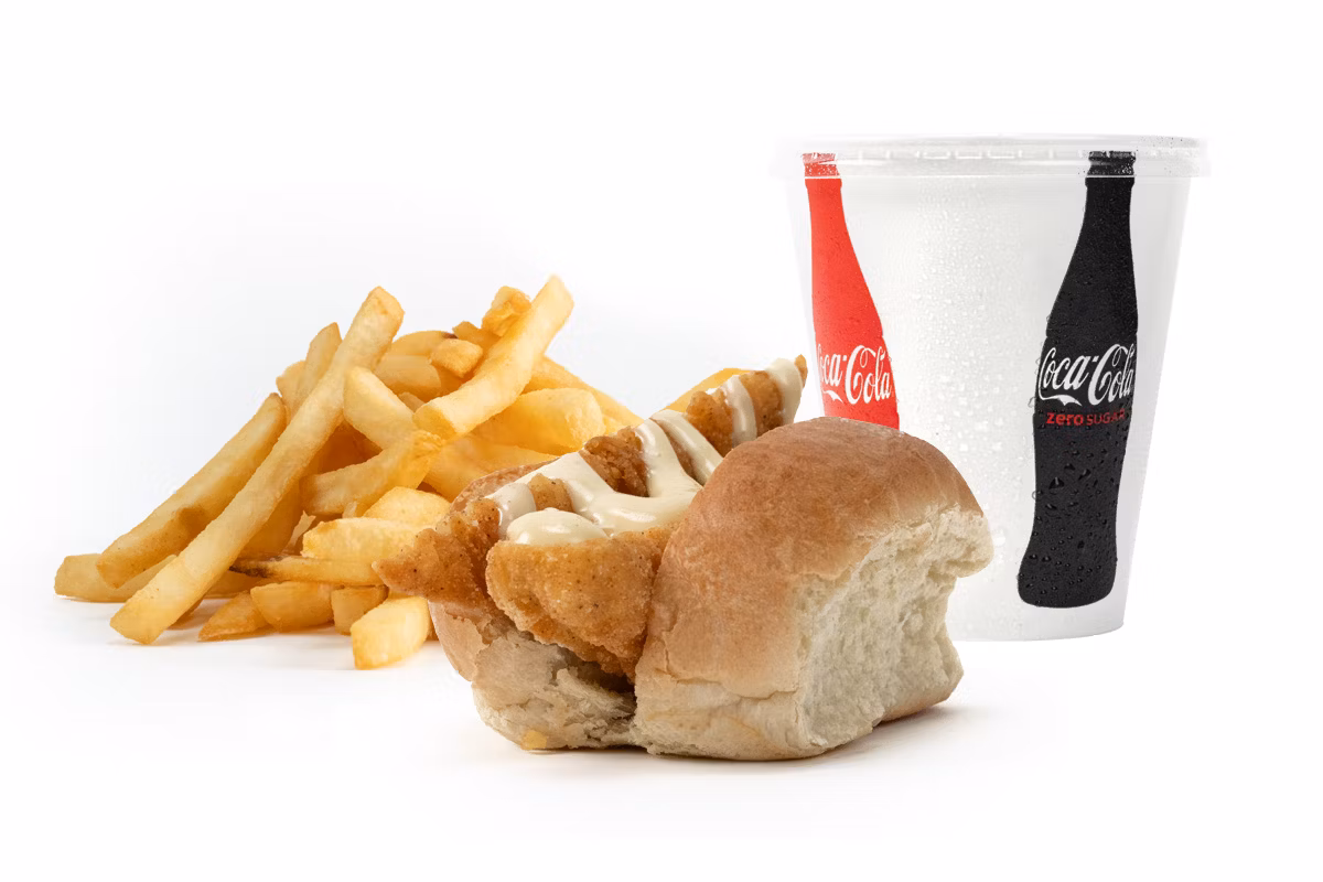 A chicken sandwich with fries and a soft drink in a cup, placed on a white background.