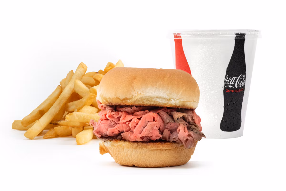 Roast beef sandwich with a side of French fries and a cup of soft drink on a white background.
