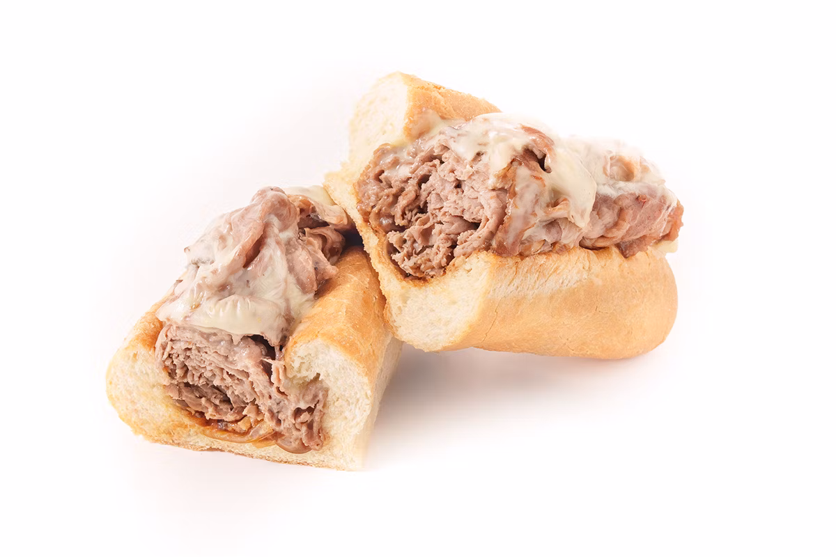 Two halves of a roast beef sandwich with melted cheese on a white background.