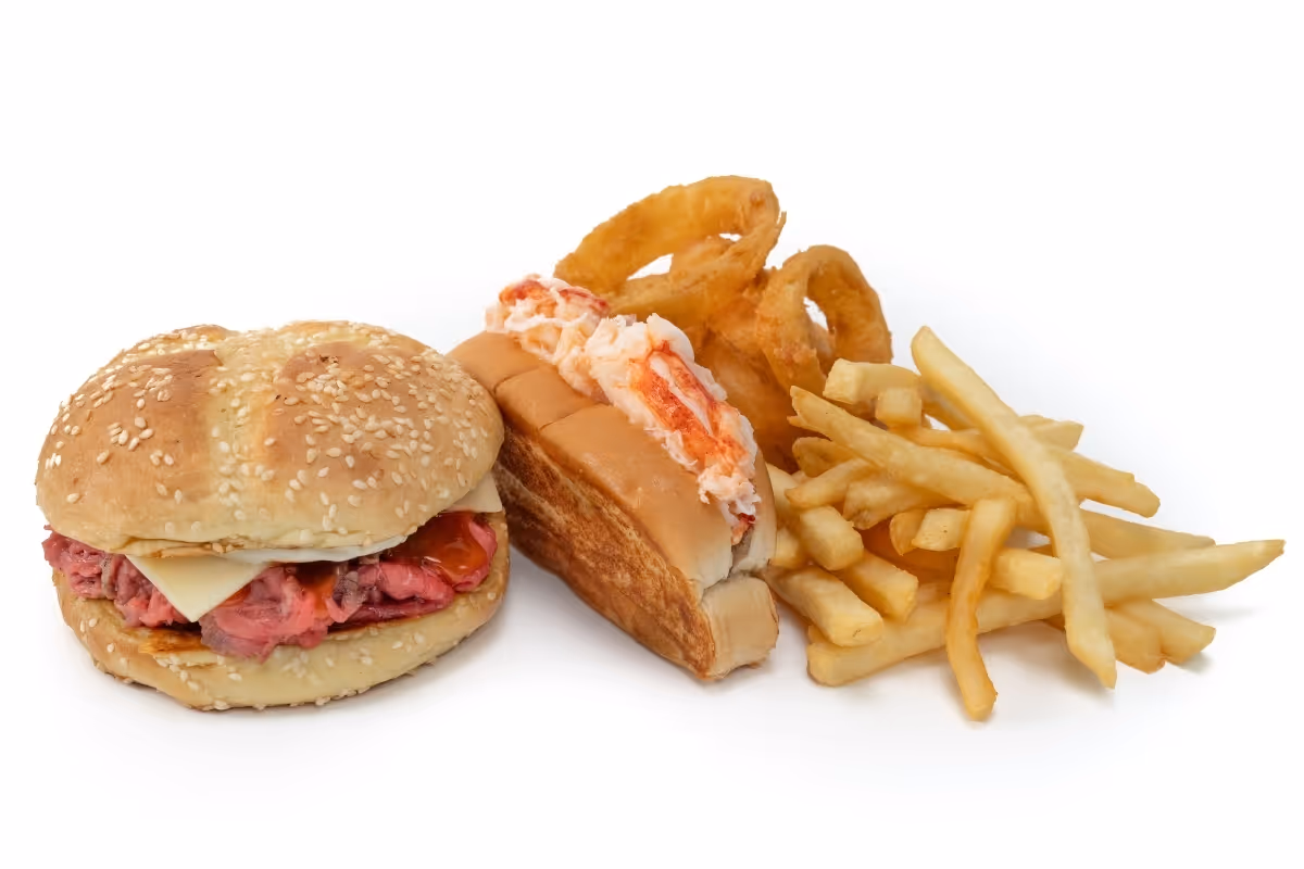 A roast beef sandwich, a lobster roll, onion rings, and French fries are arranged on a white background.
