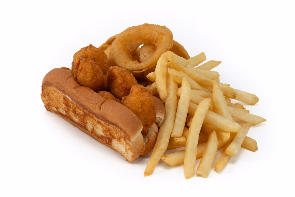 A hot dog bun filled with fried scallops, served with French fries and onion rings on a white background.