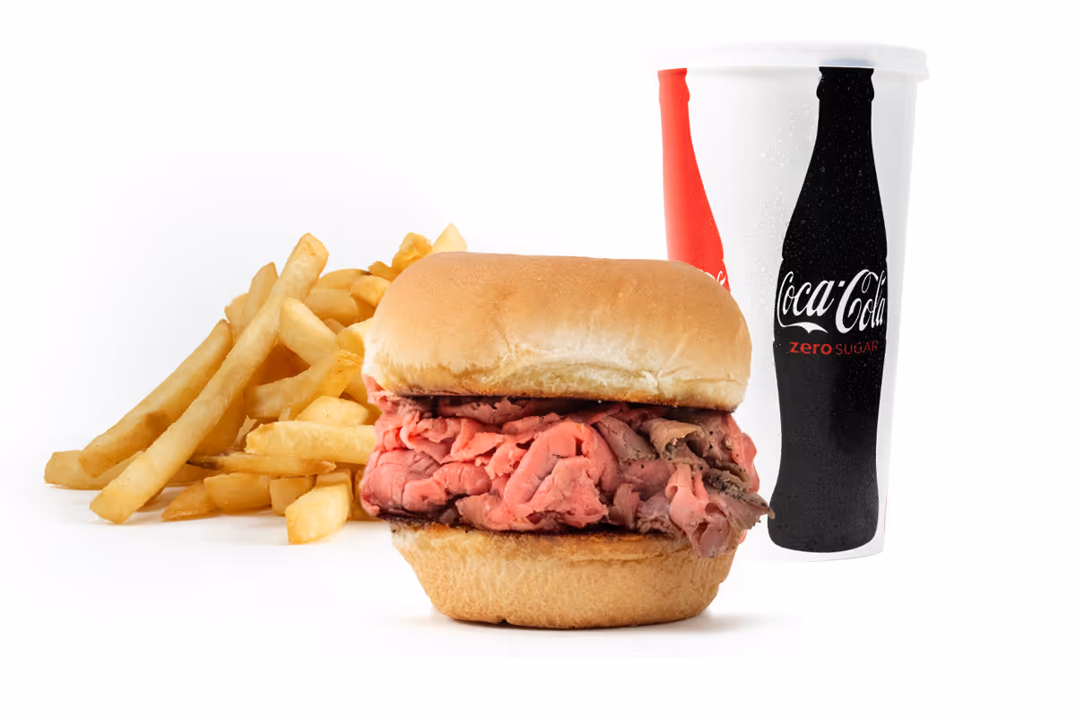 Roast beef sandwich with a side of French fries and a large Coca-Cola cup in the background.