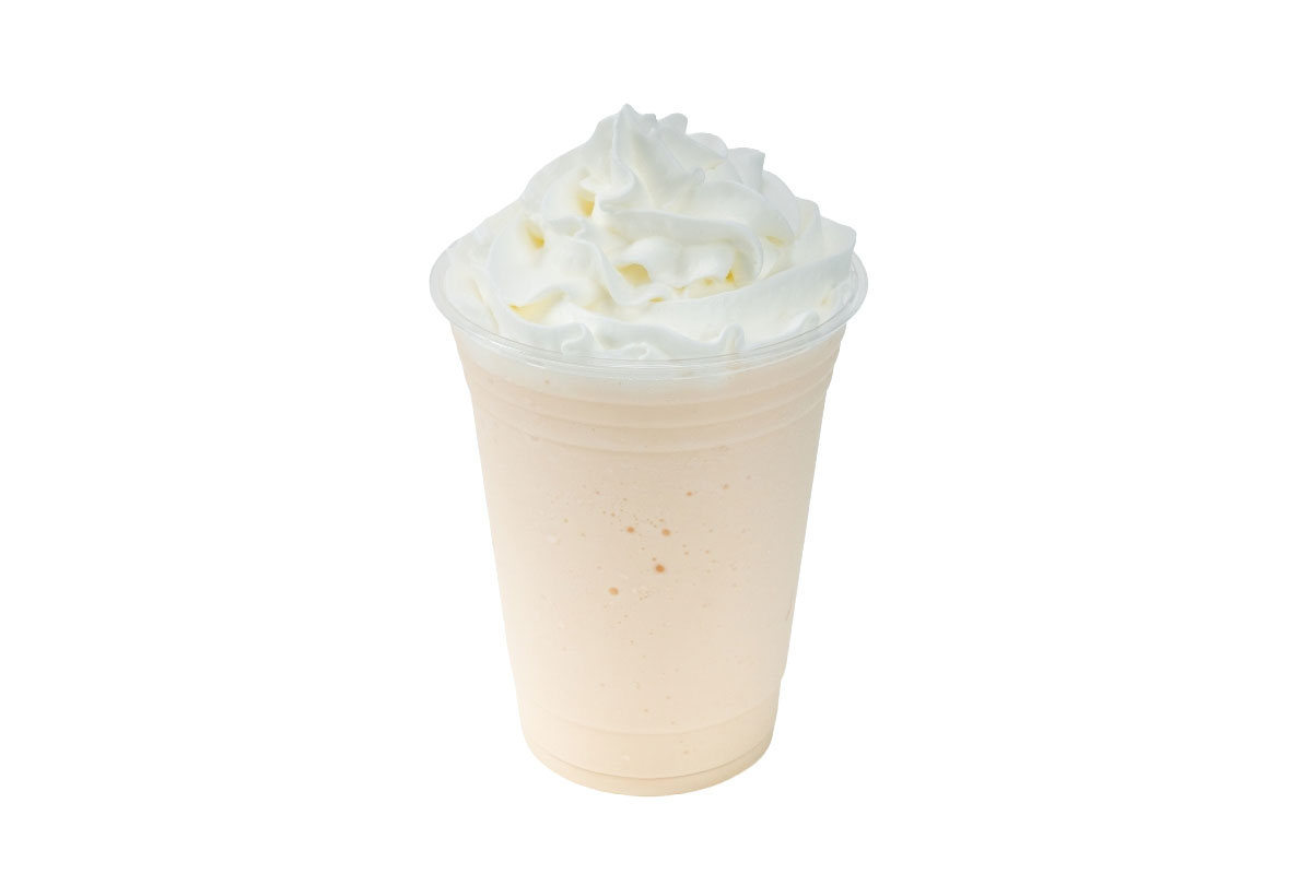 A creamsicle frappe in a clear plastic cup topped with swirled whipped cream, set against a white background.