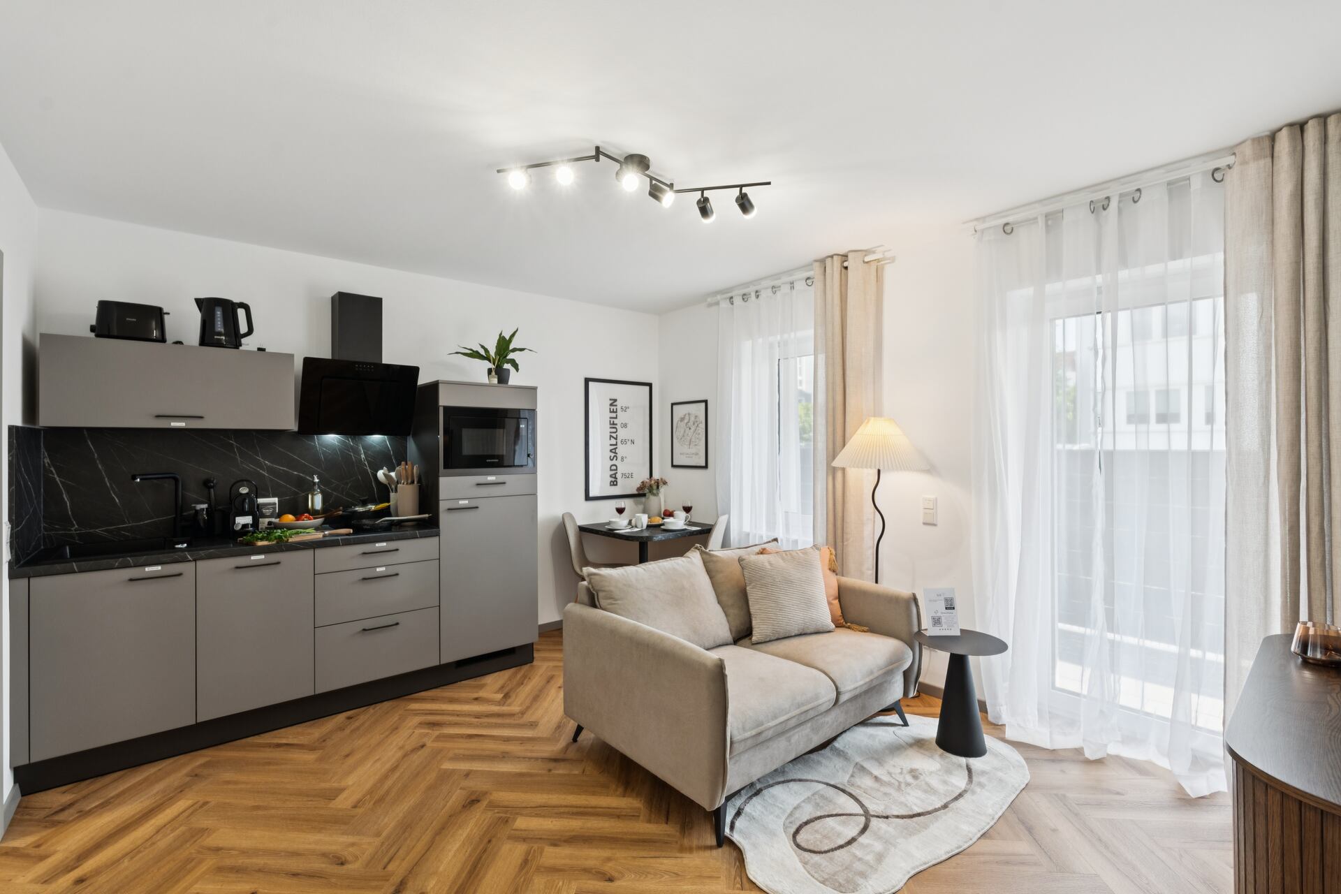 Wohn- Essbereich mit einer hellen Couch und einer grauen Küche