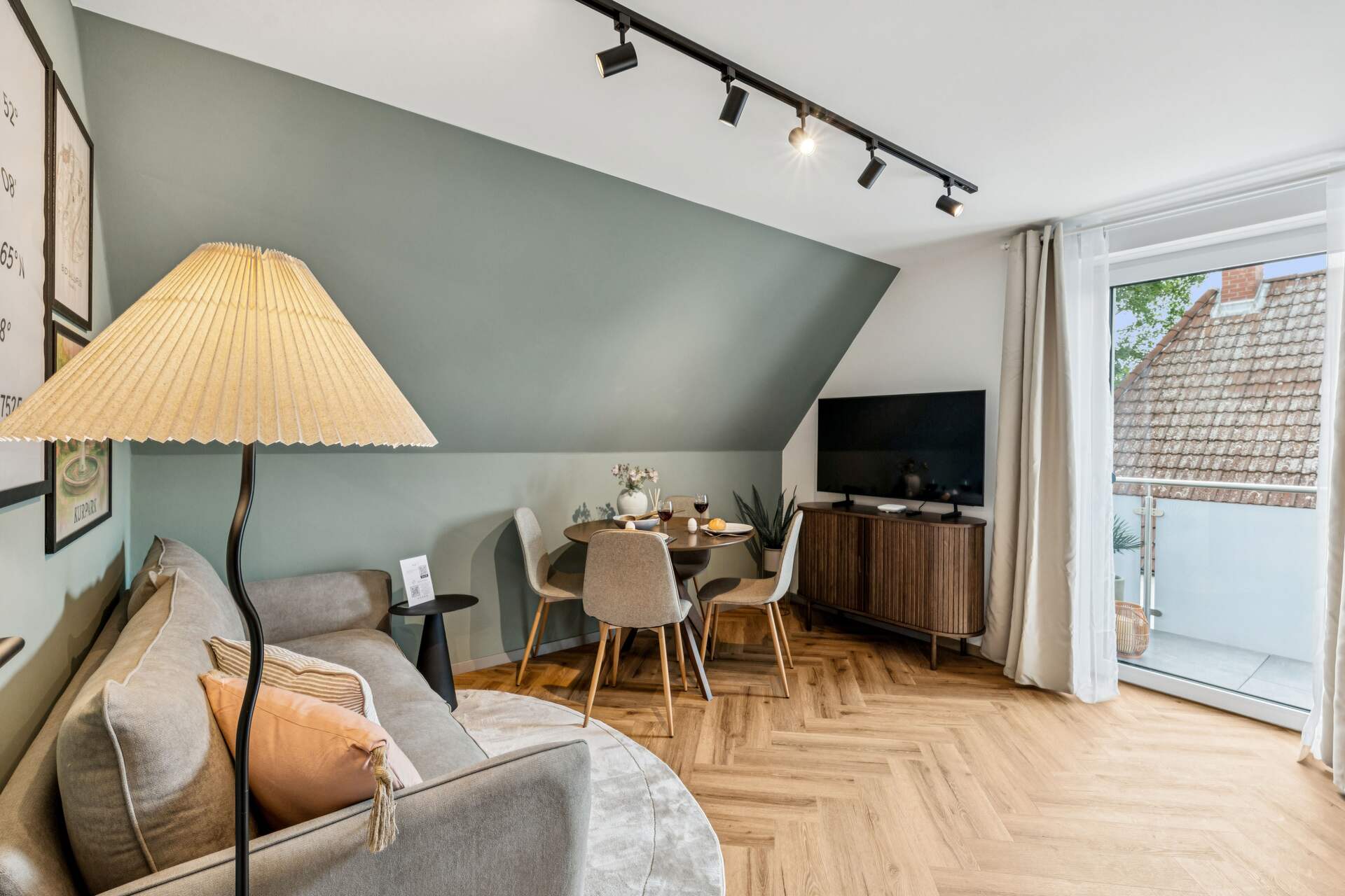 Heller Wohn- und Essbereich im Apartment am Kurpark Bad Salzuflen mit Esstisch, Sofa, TV und Zugang zum Balkon.
