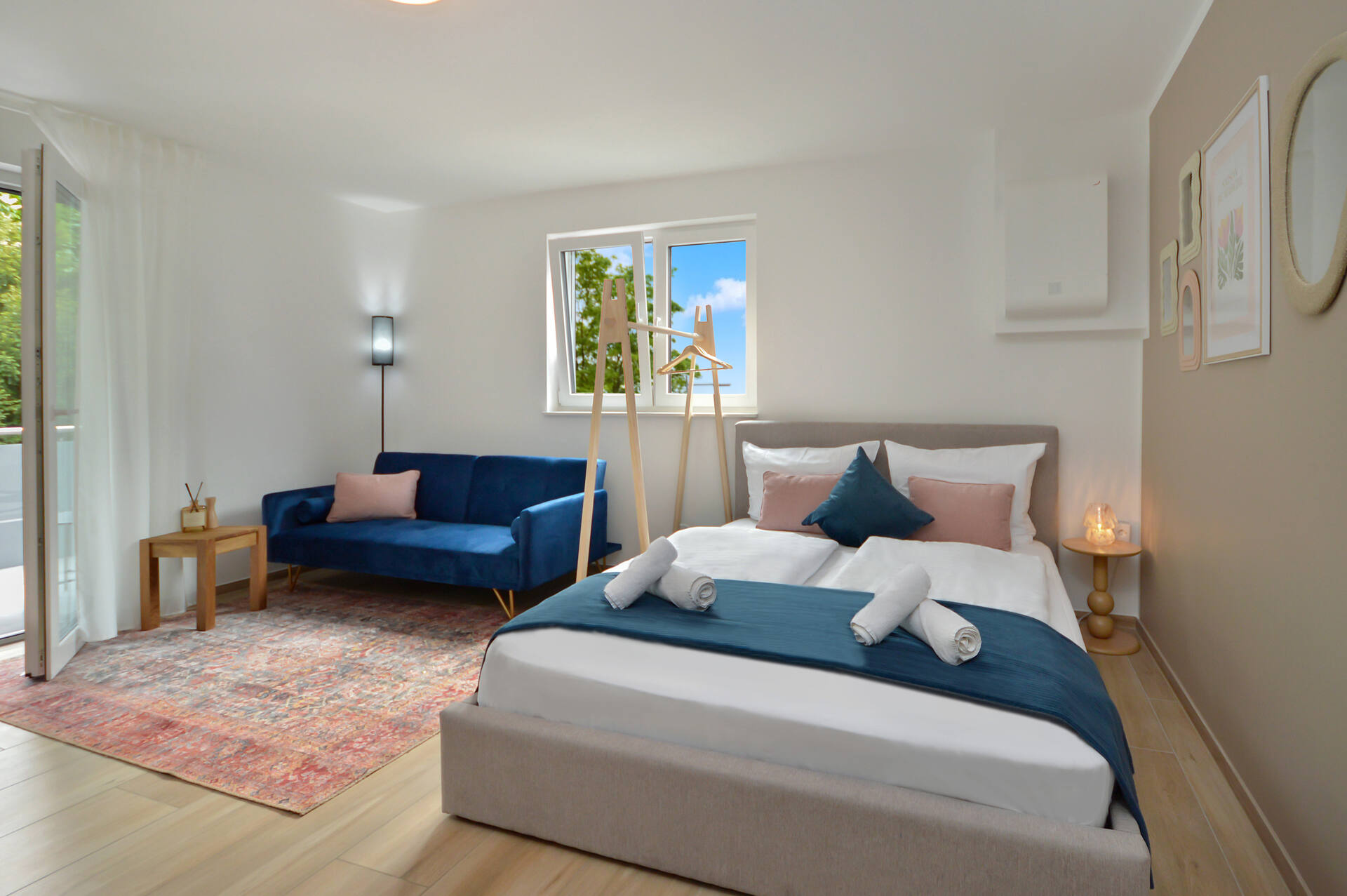 Helles Studio-Apartment in Bielefeld-Schildesche mit Doppelbett, blauer Couch und Balkonzugang – modernes Design und gemütliche Atmosphäre.