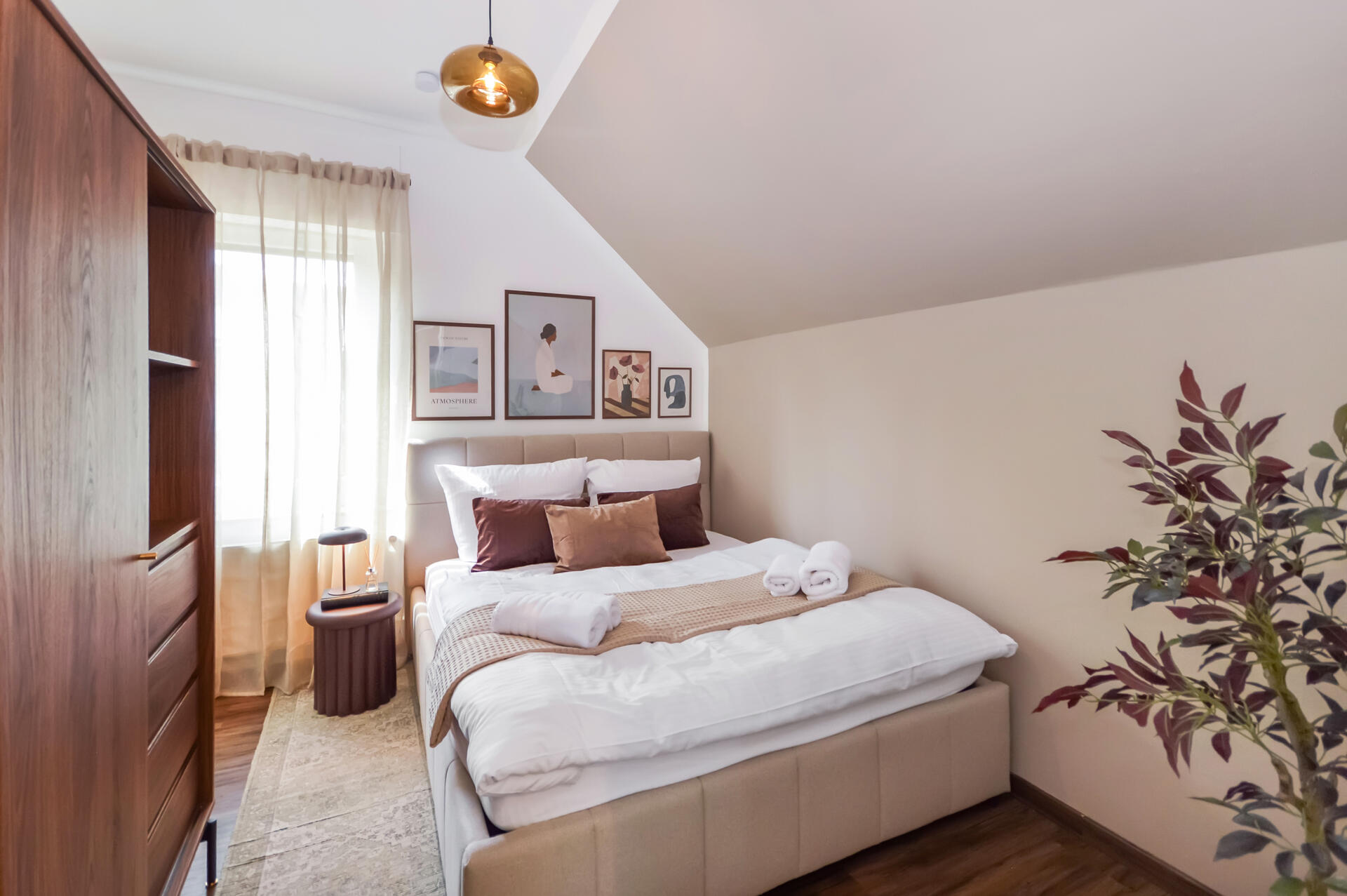 Zentrales Schlafzimmer mit gepolstertem Kopfteil, zwei Nachttischen mit Lampen, grün lackierter Akzentwand, Fenster mit Vorhängen und Deckenleuchte.