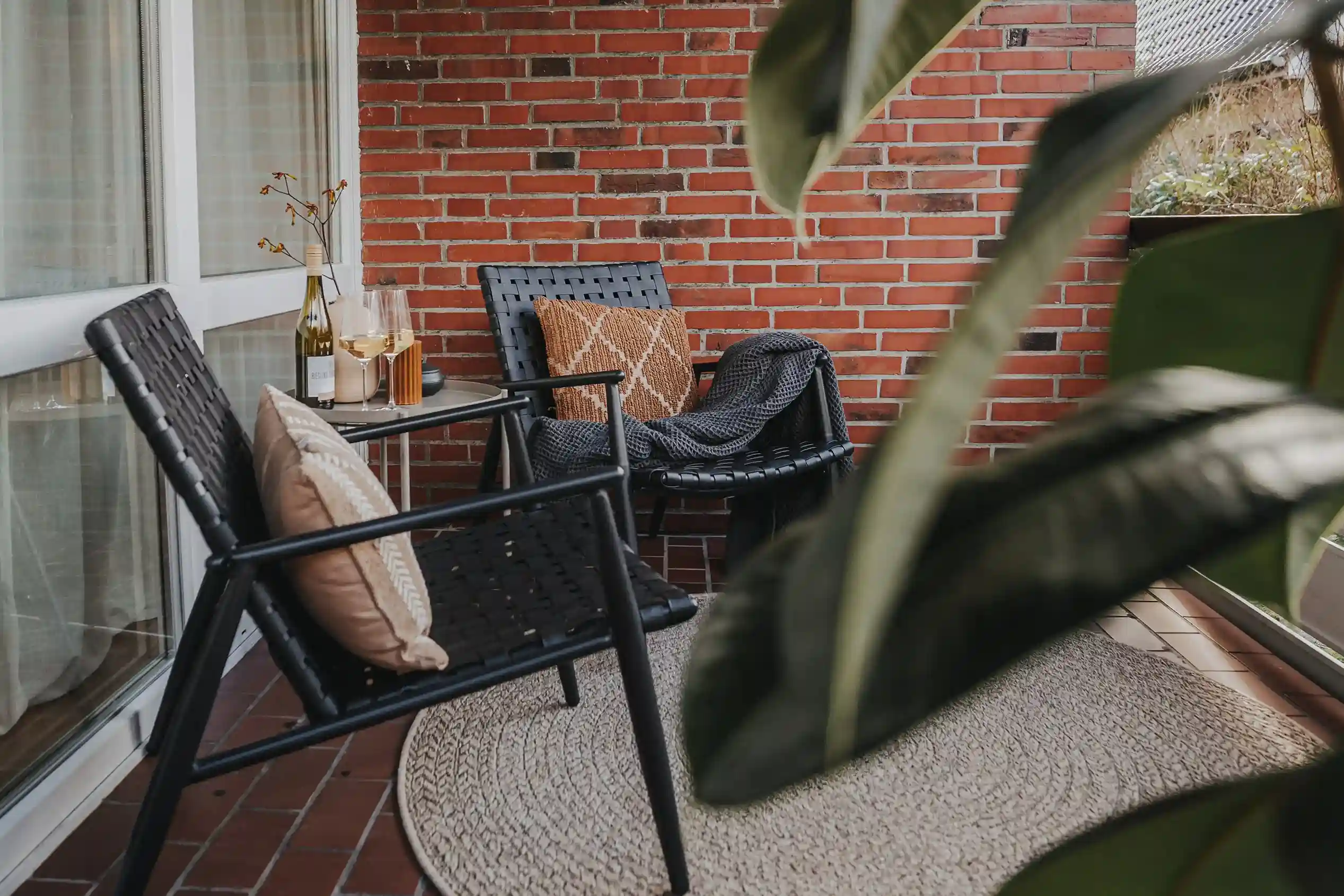 Balkon mit Stühlen, Kissen und Wein