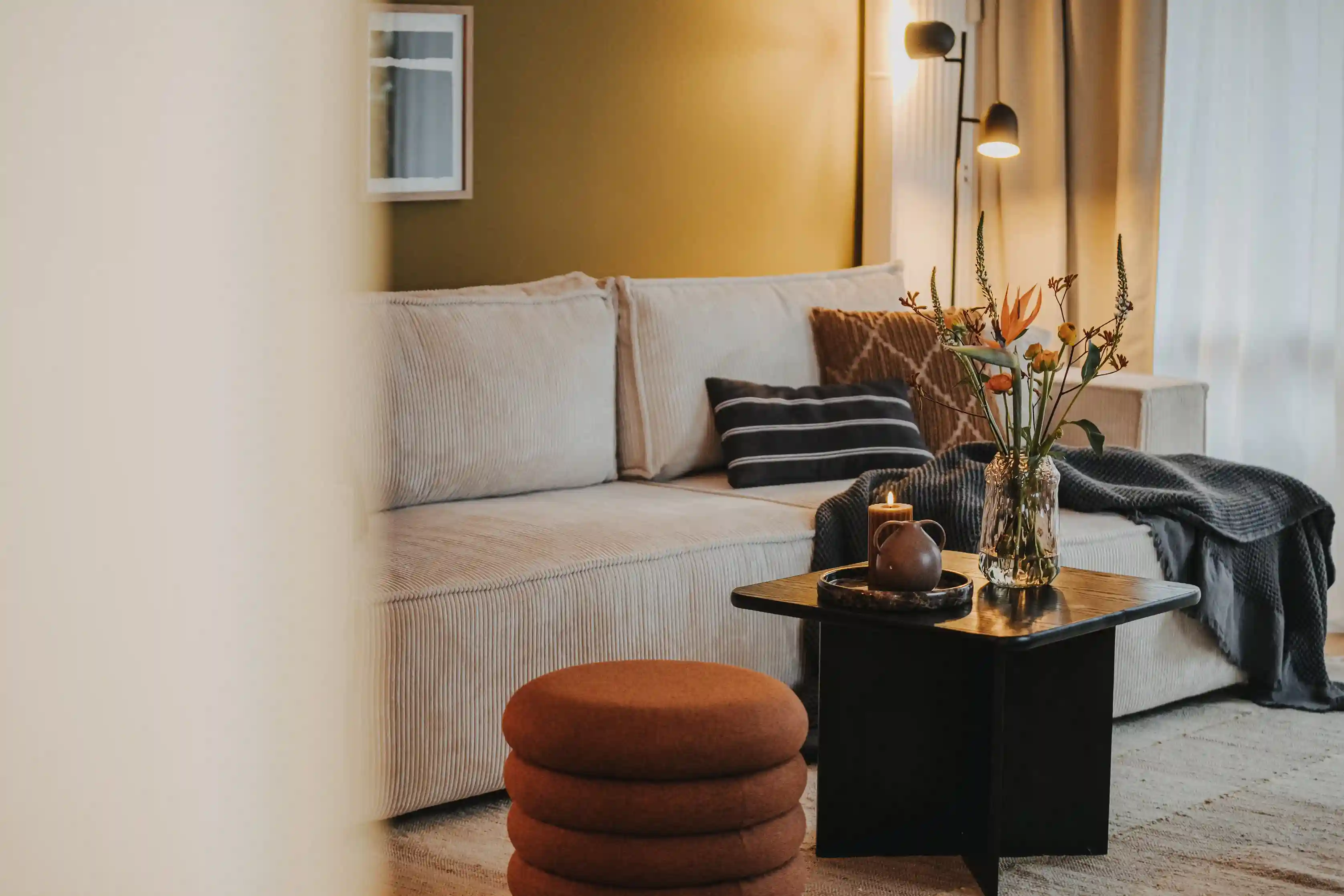 Wohnzimmer mit Sofa, Blumen und Kerze auf Tisch