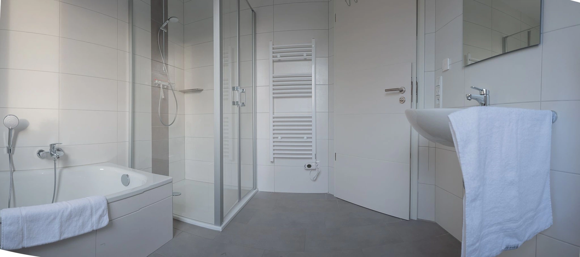 Badezimmer mit Badewanne, bodengleicher Glasdusche und Handtuchheizkörper