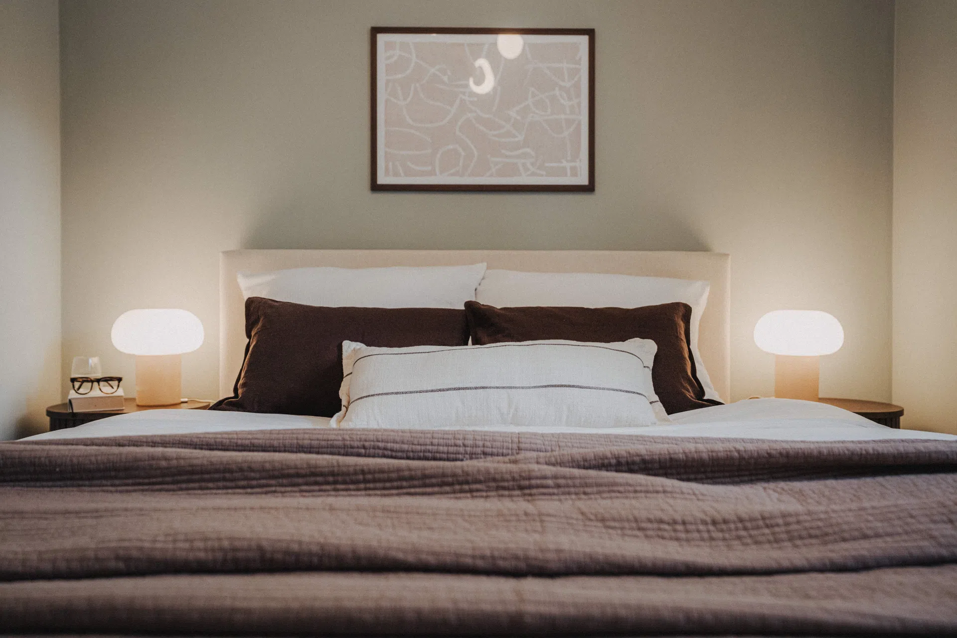 Queensize-Doppelbett mit hellen Kissen und Leselampen an beiden Seiten