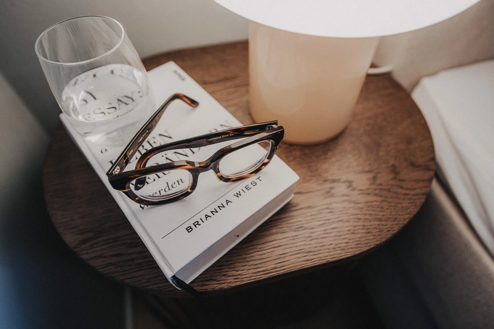 Ablagetisch am Sofa mit Lampe, Buch und Wasserglas