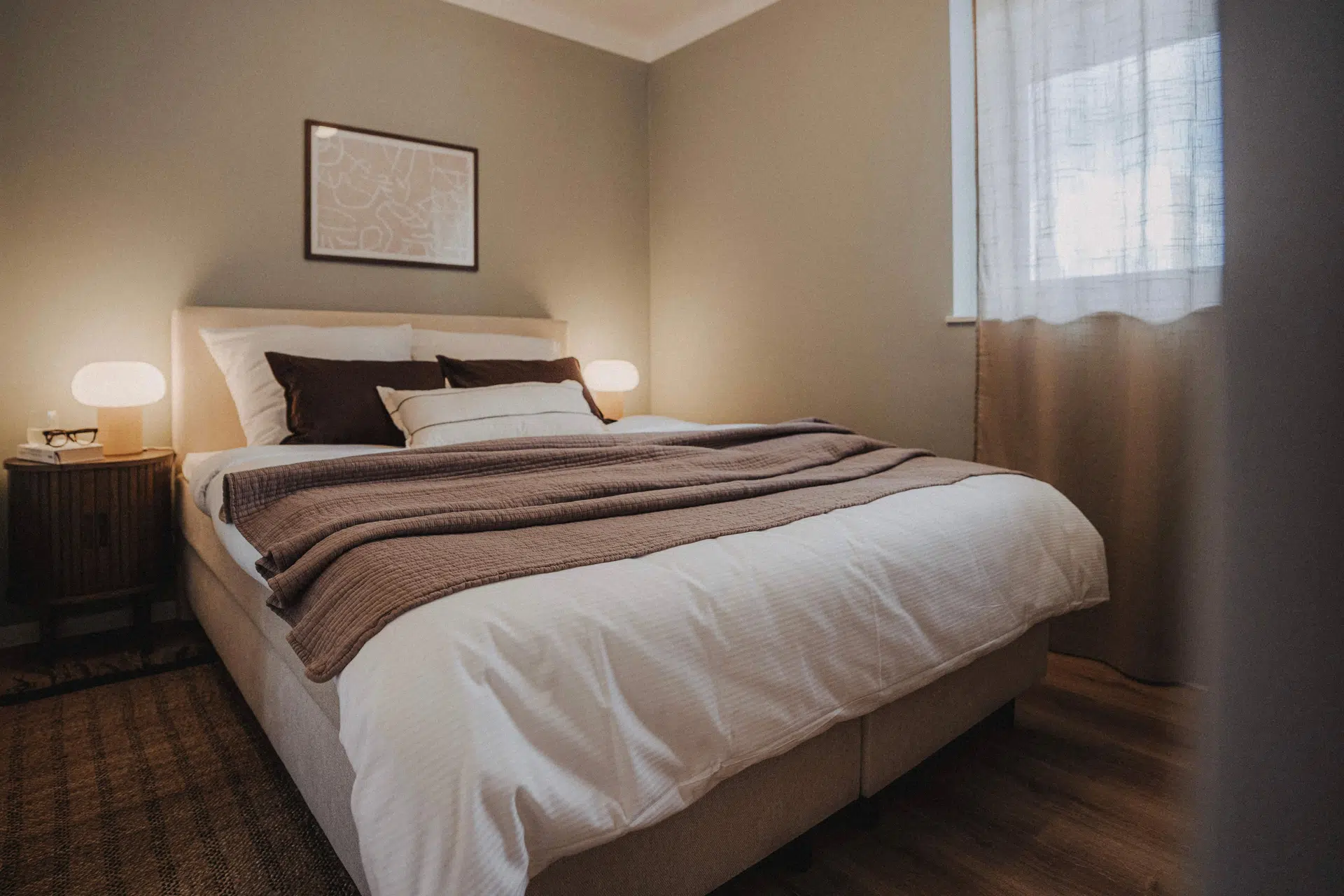 Bett mit brauner Tagesdecke und zwei Leuchten