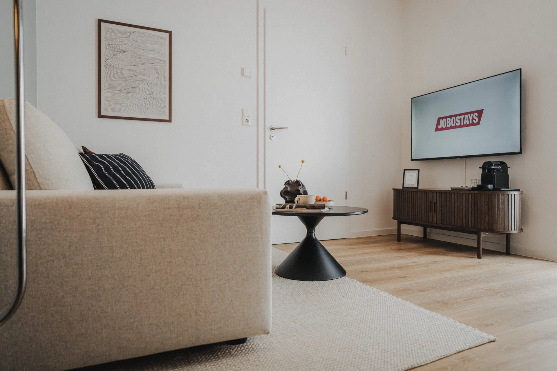 Wohnzimmer mit Sofa, Wandfernseher und dunklem Sideboard