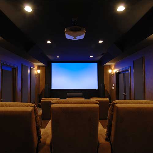 Home theater with beige recliner chairs facing a large blank projection screen in a dimly lit room.