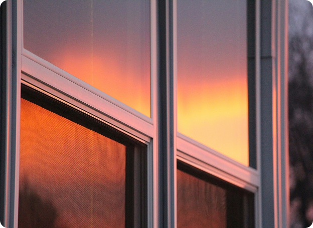 Reflection of a vibrant orange and pink sunset in glass window panes of a modern building.