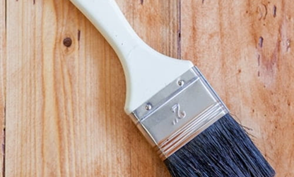 Close-up of a paintbrush with black bristles resting on a wooden surface.
