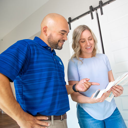 Man and woman looking at and discussing a color swatch book indoors.