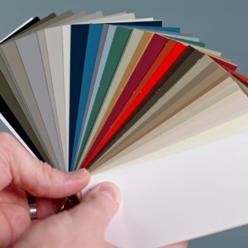 Hand holding a fanned-out set of color swatches ranging from neutral tones to reds and blues.