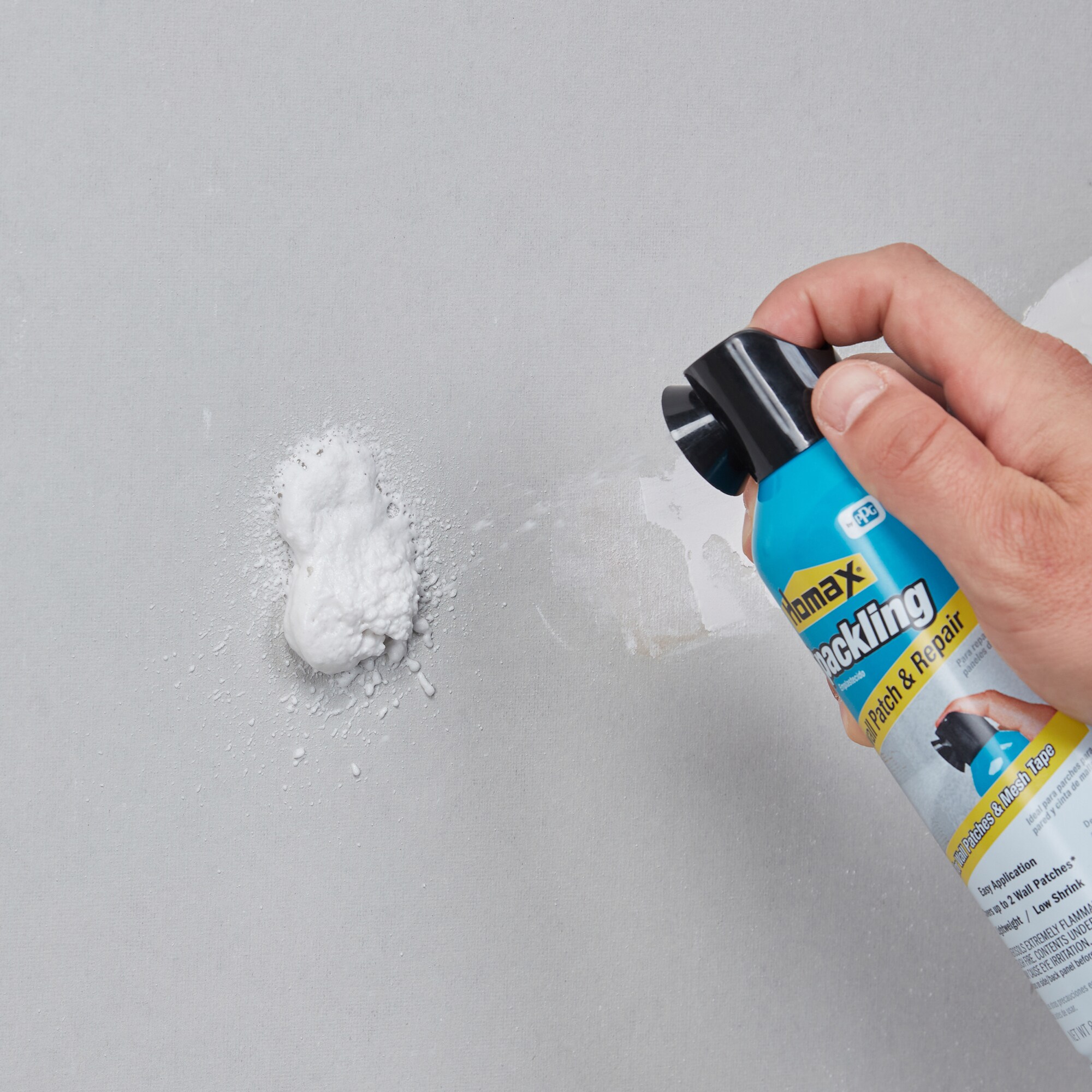 Hand spraying foam patch and repair spray onto a wall to fill a hole or damage.