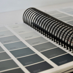 Open color swatch book featuring various shades of grey with a black spiral binding.