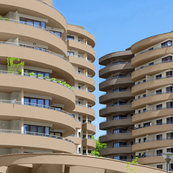 Curved balconies on two modern multi-story residential buildings under a clear blue sky.