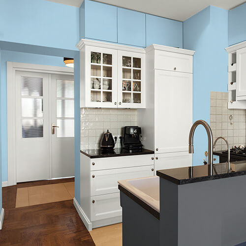 Modern kitchen with light blue walls, white cabinets, black countertop, and a sink with a tall faucet on a gray island.