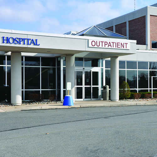Entrance to hospital outpatient department with glass doors and blue sky above.