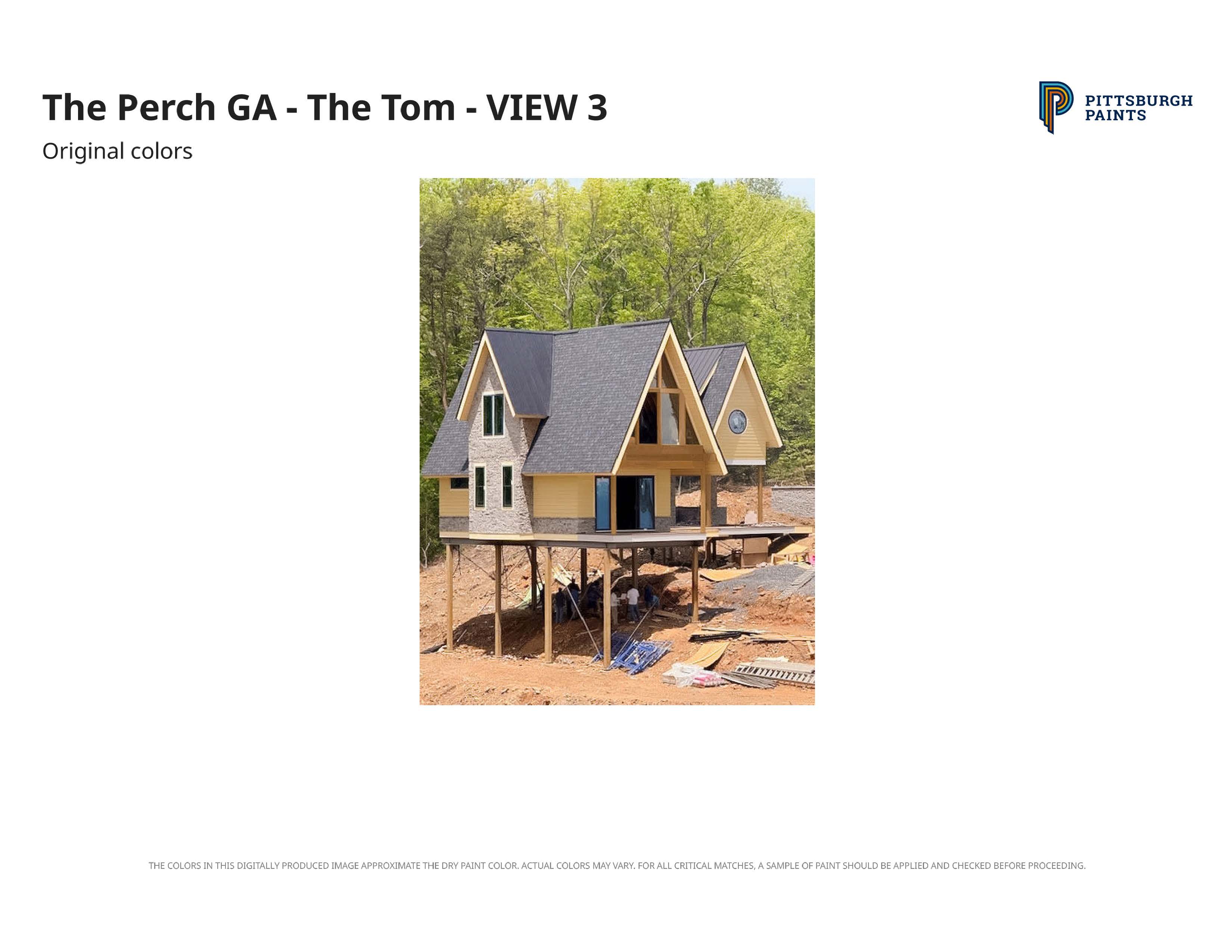 House under construction elevated on stilts with steep roofs surrounded by trees and dirt ground.