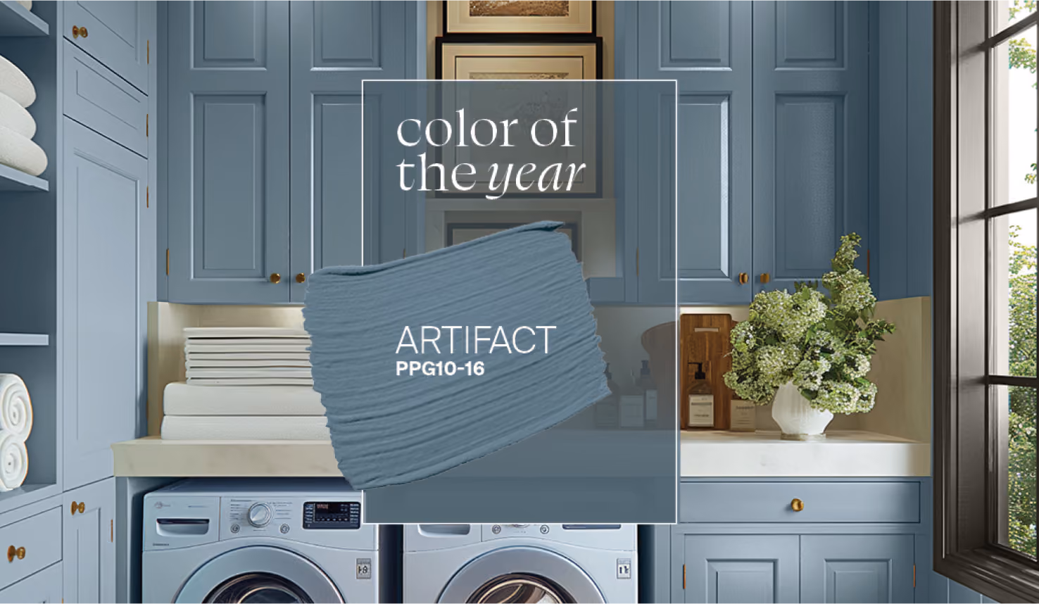 A modern laundry room interior featuring blue-grey painted cabinets and a color sample card overlay displaying Artifact Color of the Year